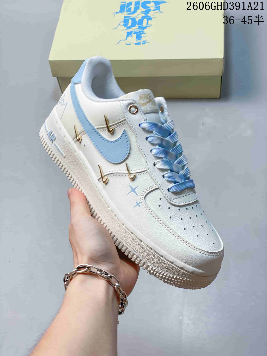 Angled side view of the white sneaker with light blue and gold-tone details