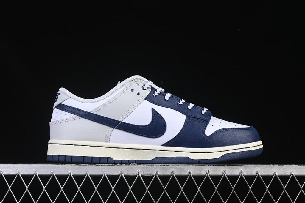 Side profile of the low-top sneaker with navy overlays and a light midsole
