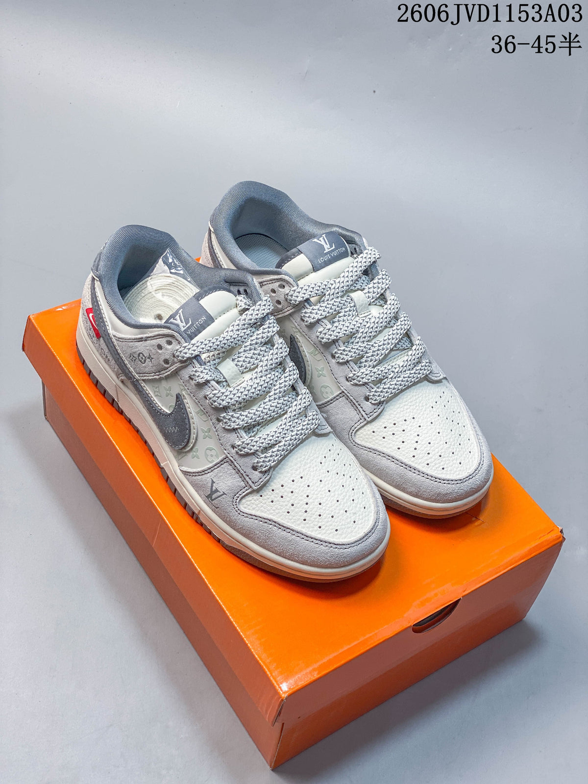 Pair of grey and white low-top sneakers shown on an orange box