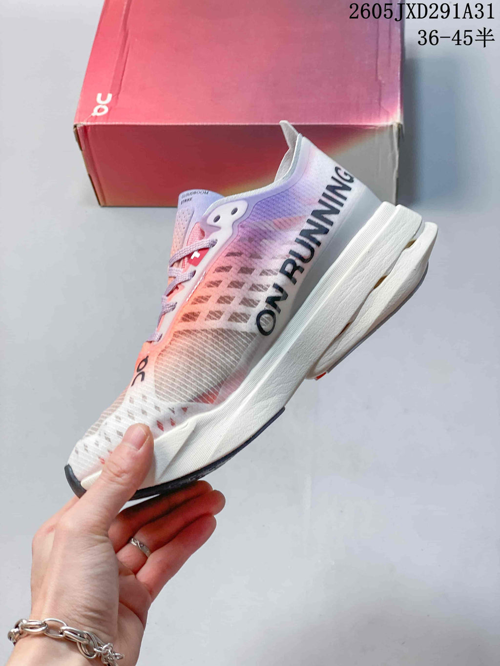Side view of an On Cloudboom Strike shoe with coral and lilac detailing and a high-profile midsole.
