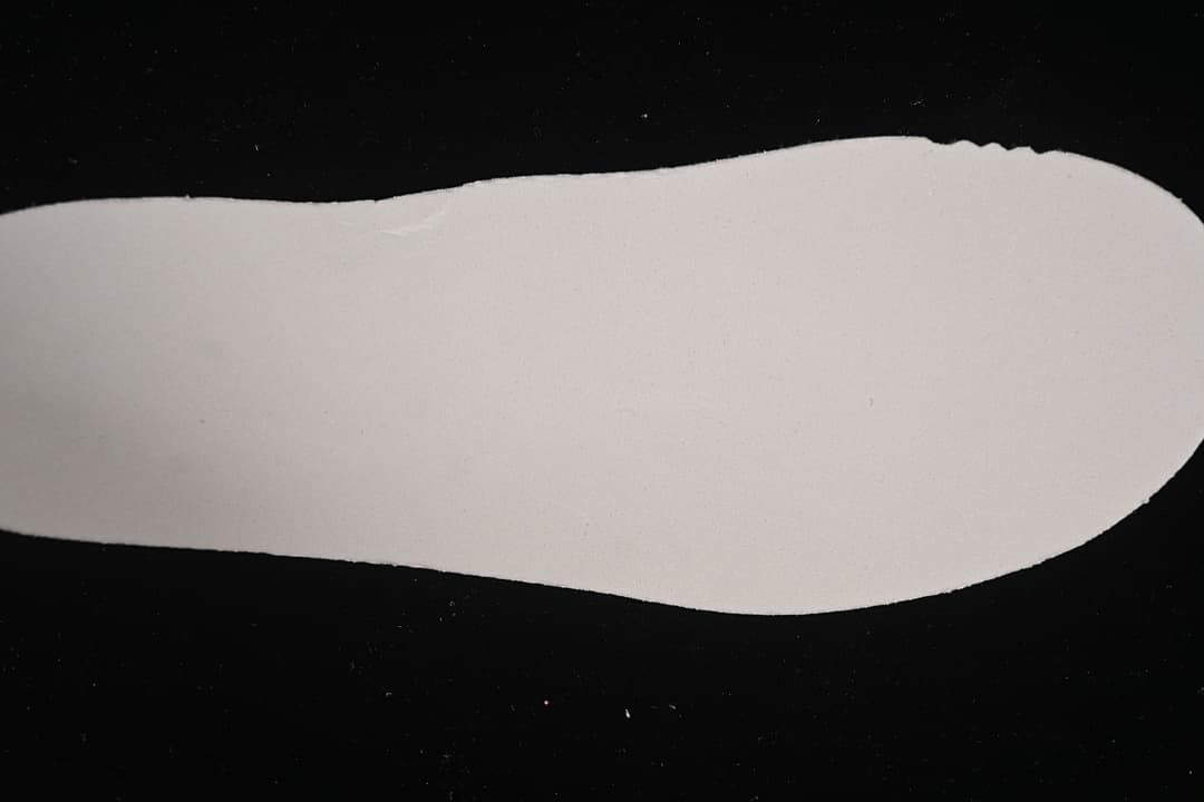 Plain light-colored shoe-shaped cutout shown against a dark background.