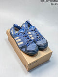 Pair of blue Adidas outdoor shoes with cream side stripes and cord-style laces, shown on a box