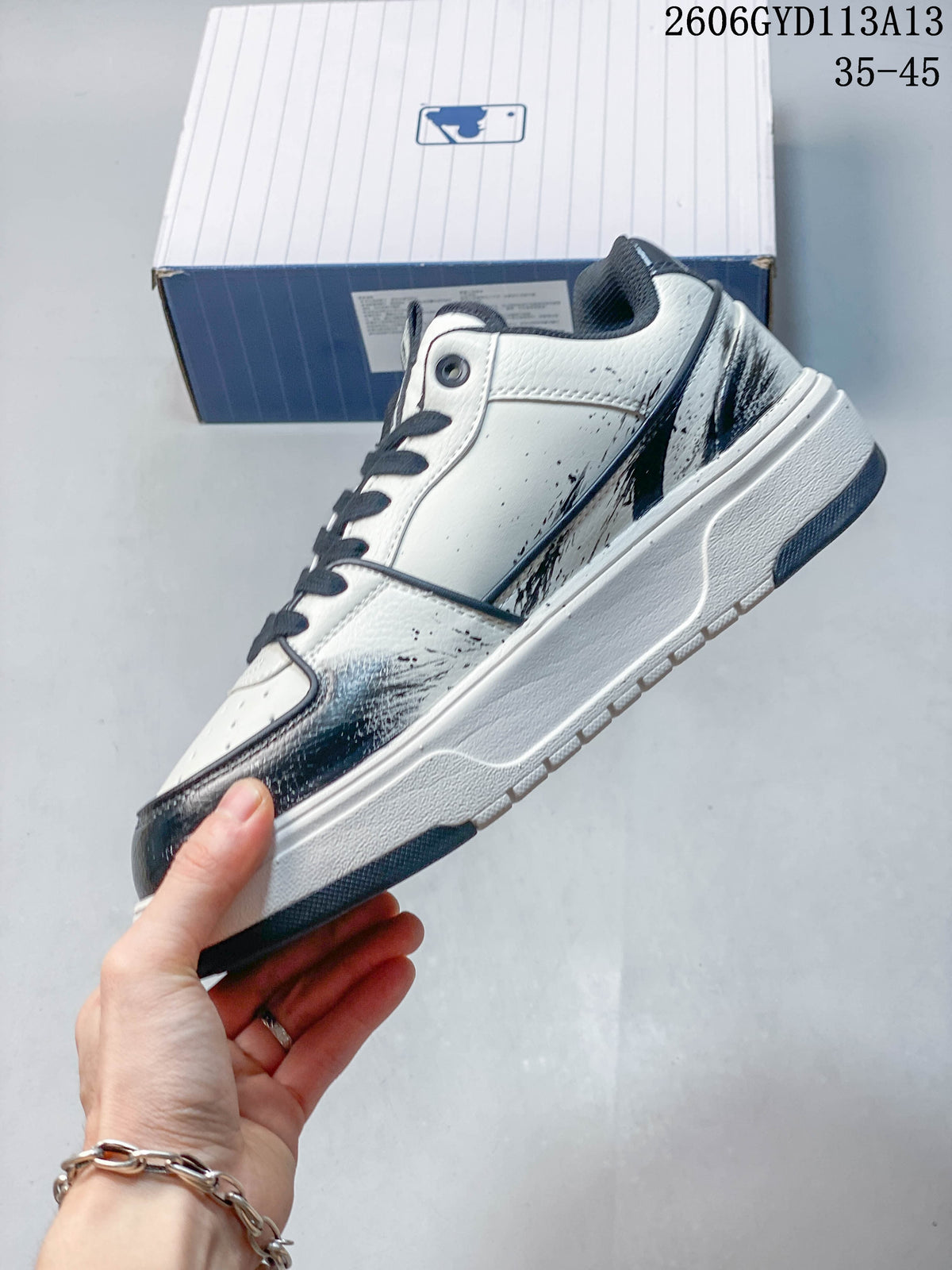 Side profile of the white sneaker with navy and dark brushstroke graphics