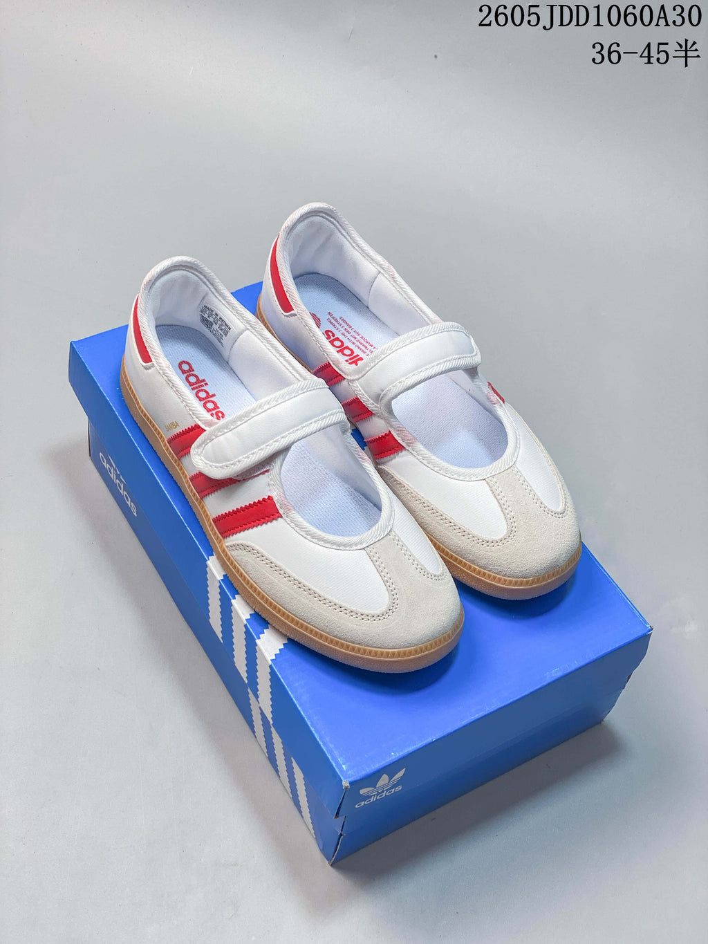 Pair of white Adidas Samba Jane sneakers with red stripes, hook-and-loop straps, and gum-colored soles