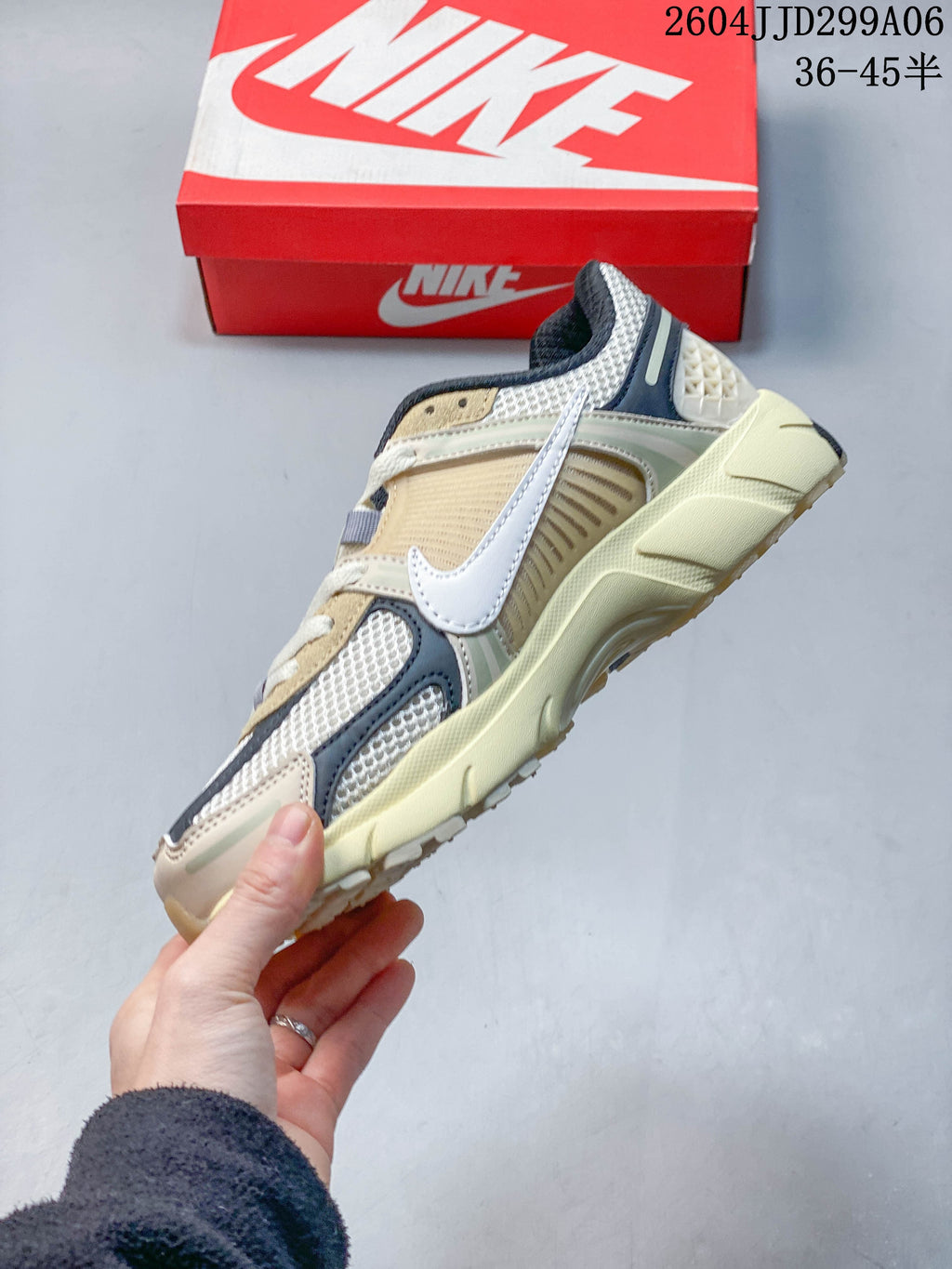 Side profile of a beige Nike Zoom Vomero 5 sneaker with mesh panels and a white Swoosh.