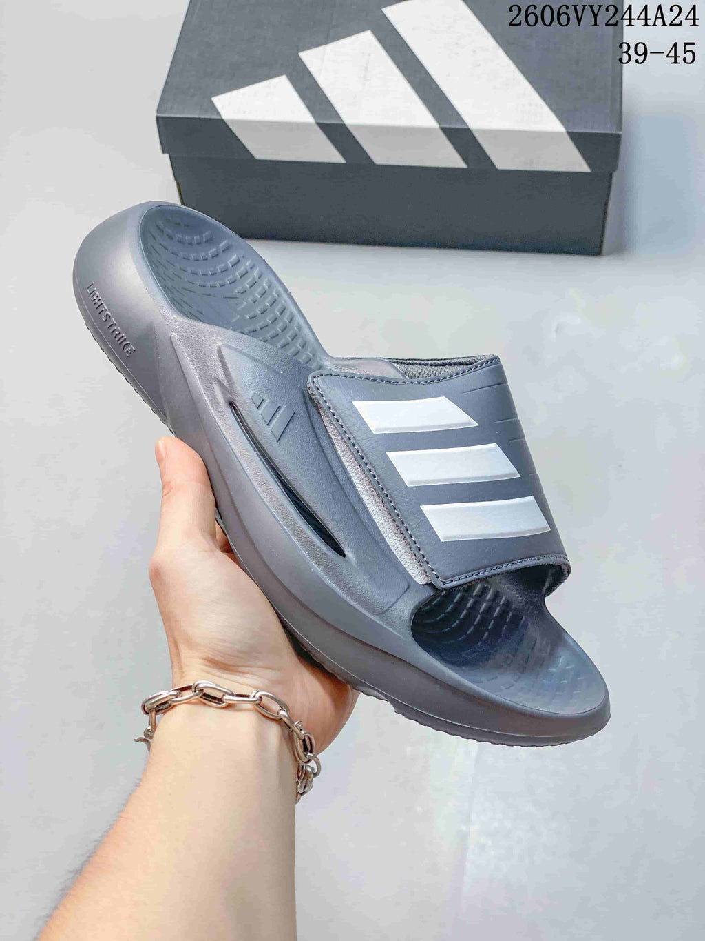 Gray adidas Lightblaze slide with a light-colored three-stripe strap; image overlay lists sizes 39–45.