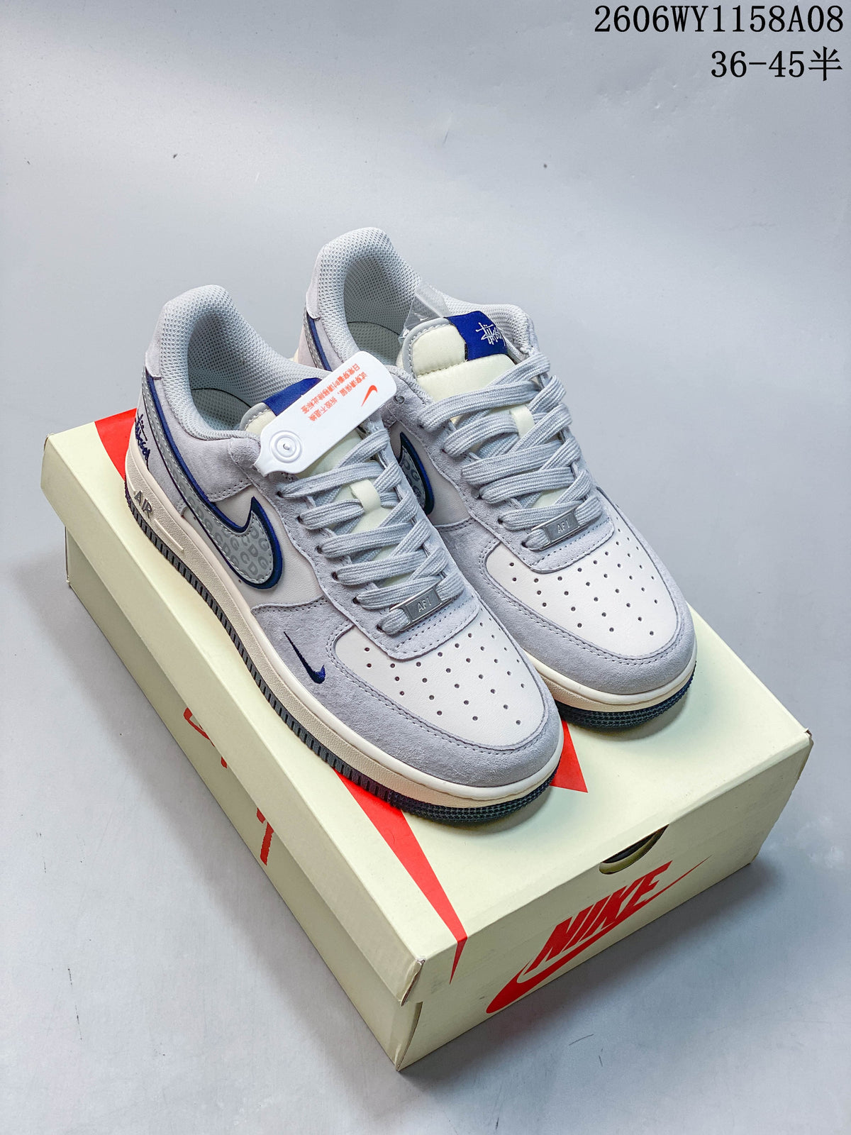 Pair of pale gray and off-white Nike Air Force 1 '07 low-top sneakers with blue accents, displayed on a shoe box