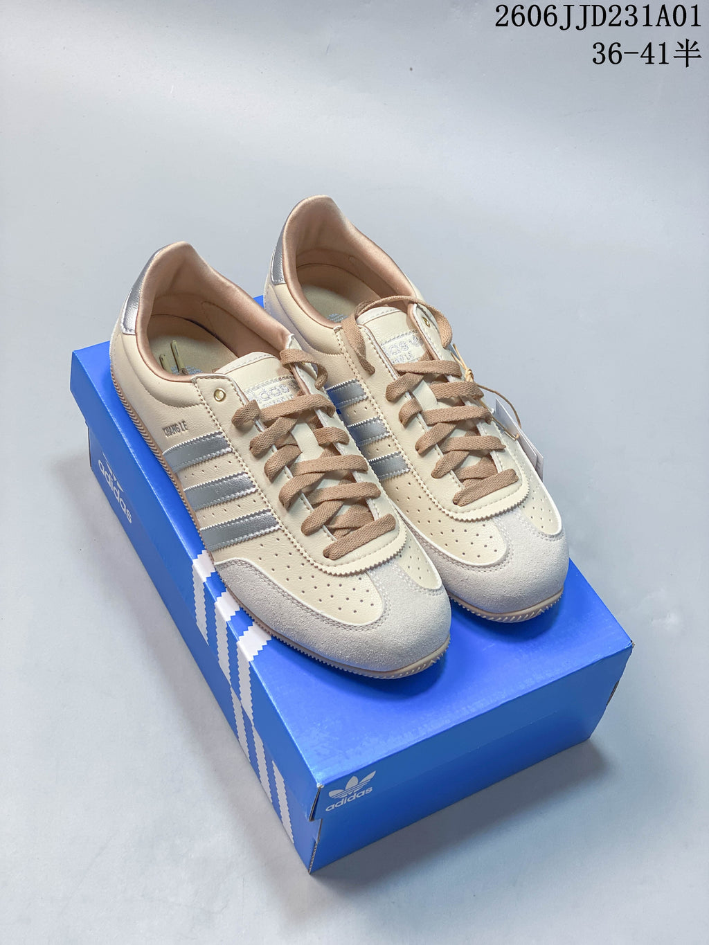 Pair of cream Adidas Changle sneakers with metallic silver stripes and tan laces.