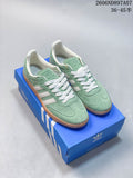 Pair of mint green and white adidas Samba sneakers on a blue shoebox