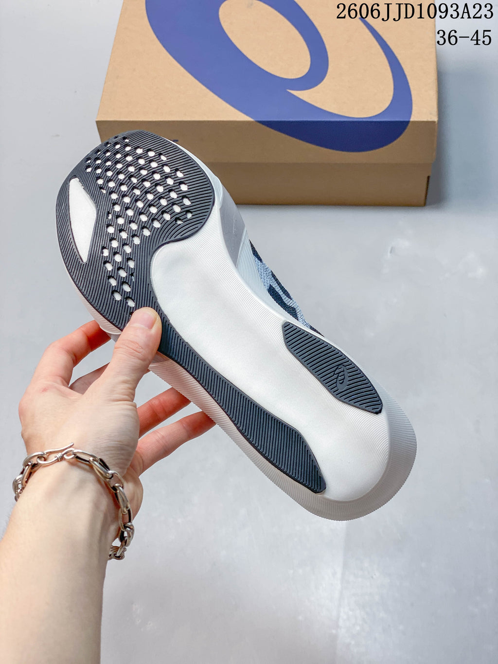 Underside of a running shoe showing a white sole with dark traction sections.