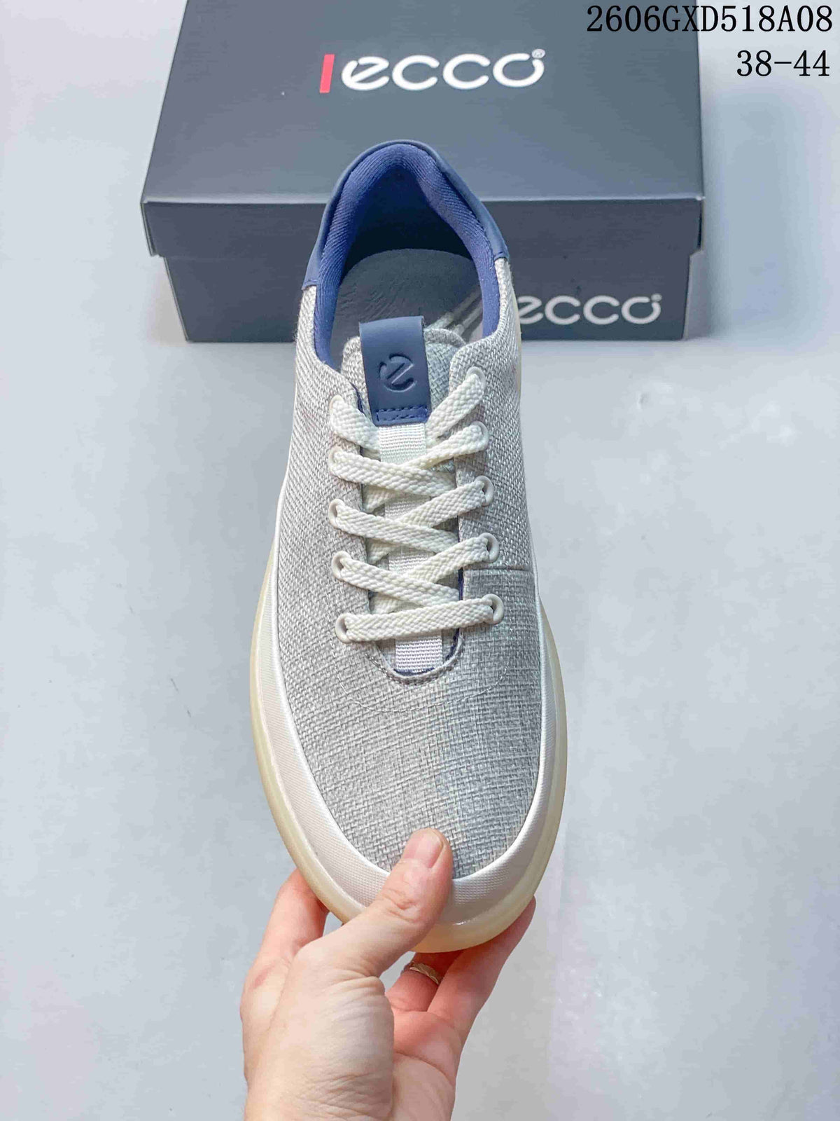 Front view of a gray sneaker with white laces and navy details.