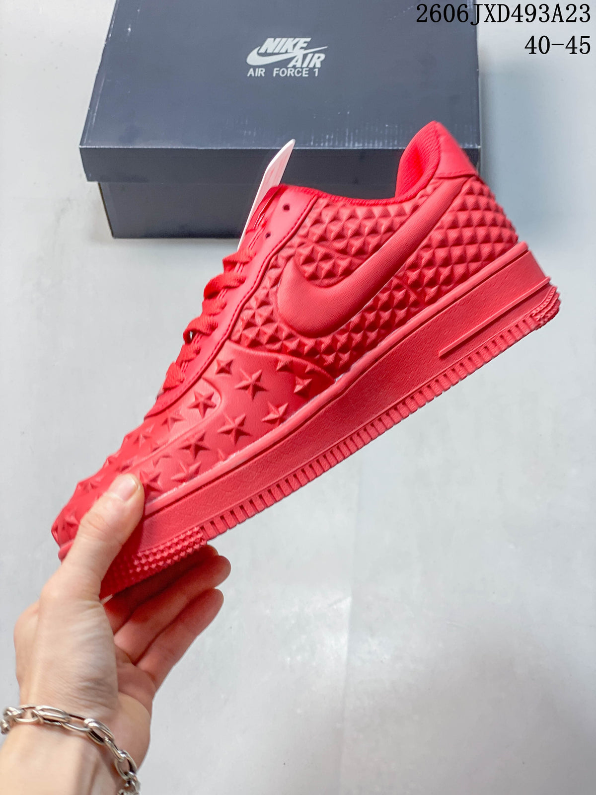 Side view of a red low-top sneaker with a Swoosh and raised star and diamond textures