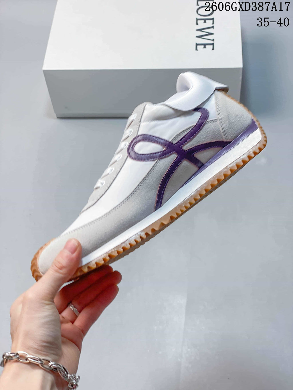 Side profile of a white sneaker with gray overlays, purple side detailing, and gum outsole