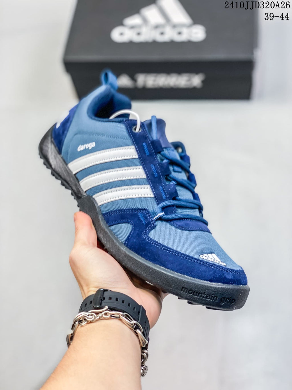 Angled side view of the blue adidas Daroga Plus Canvas shoe with white stripes and dark outsole.