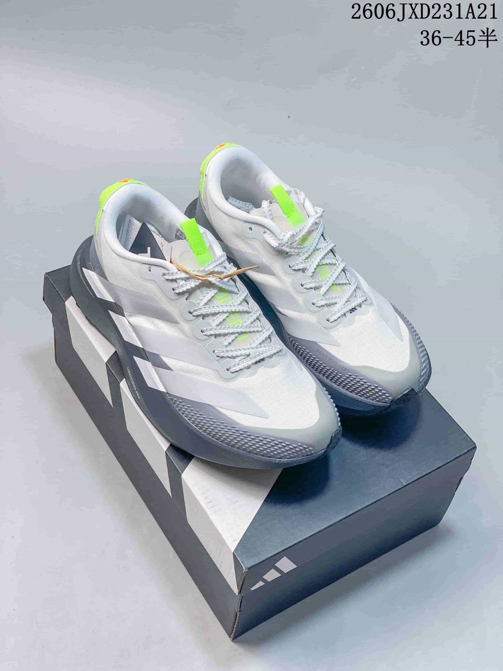 Pair of white and grey Adidas Adizero Evo SL running shoes with lime accents, shown on a shoebox.