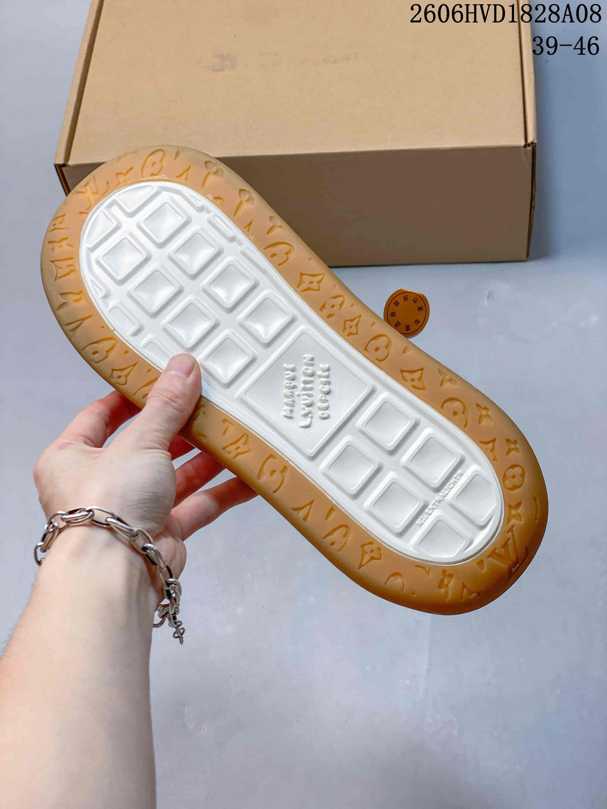 Underside of a sneaker showing white tread and a gum-colored patterned outsole