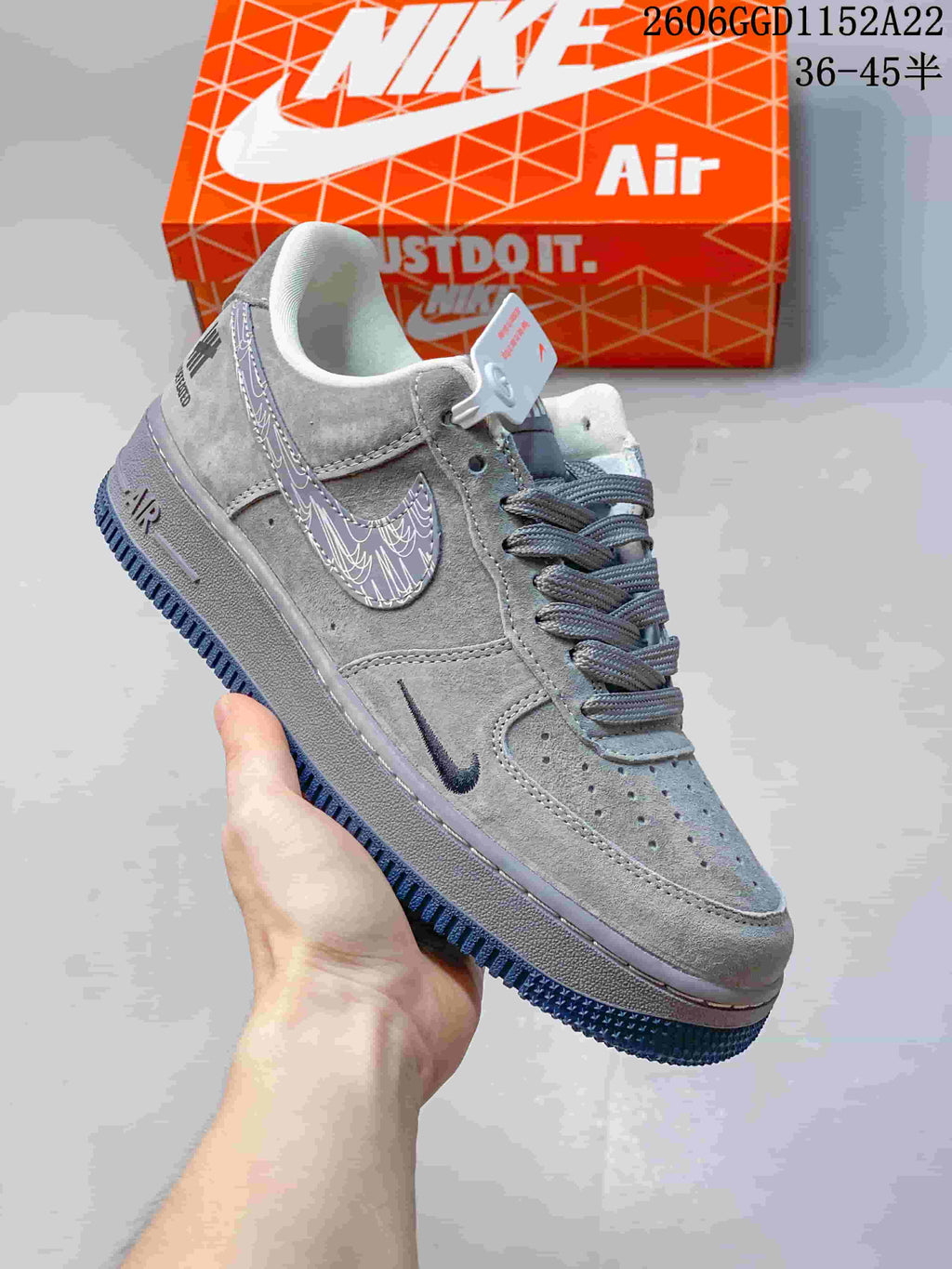 Angled view of the grey sneaker with patterned Swoosh, heel branding, and dark blue outsole