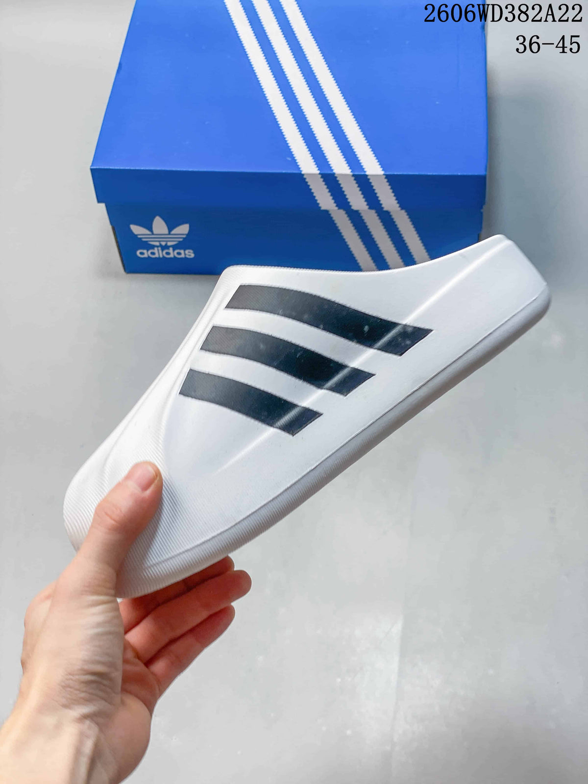 Side view of a white closed-toe slide with three black stripes