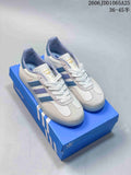 Pair of white and light-gray Adidas Gazelle low-top sneakers with blue and lavender stripes, displayed on a blue shoebox.