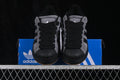Front view of grey and black Adidas Superstar 2 ST sneakers positioned on a blue shoebox.