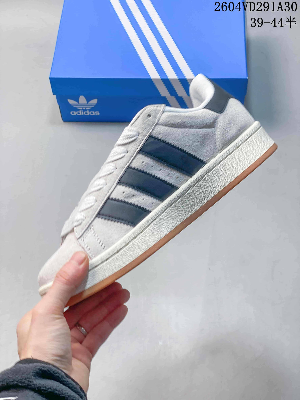 Side view of the light gray sneaker with dark stripes, an off-white midsole and gum outsole.