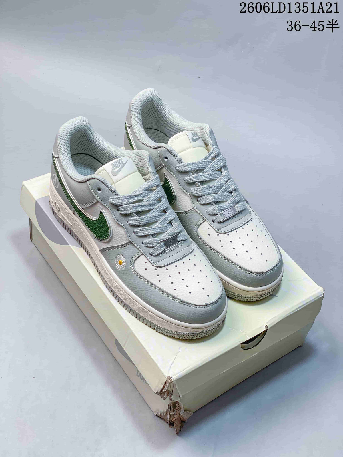 Pair of white and gray Nike Air Force 1 low-top sneakers with green glitter-look Swooshes and daisy details