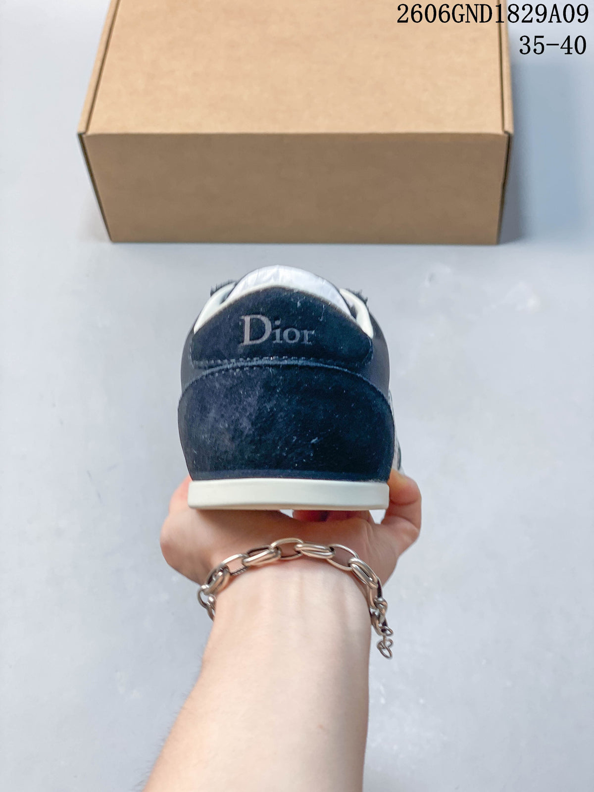 Rear view of a navy sneaker with a light-colored sole and heel branding.
