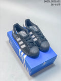 Pair of dark Adidas Superstar sneakers with white stripes and textured shell toes on a blue box.