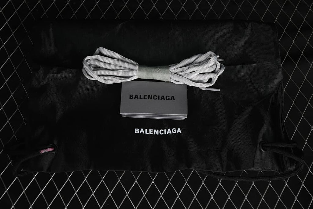 Black drawstring shoe bag and spare gray laces displayed with a Balenciaga-branded card.