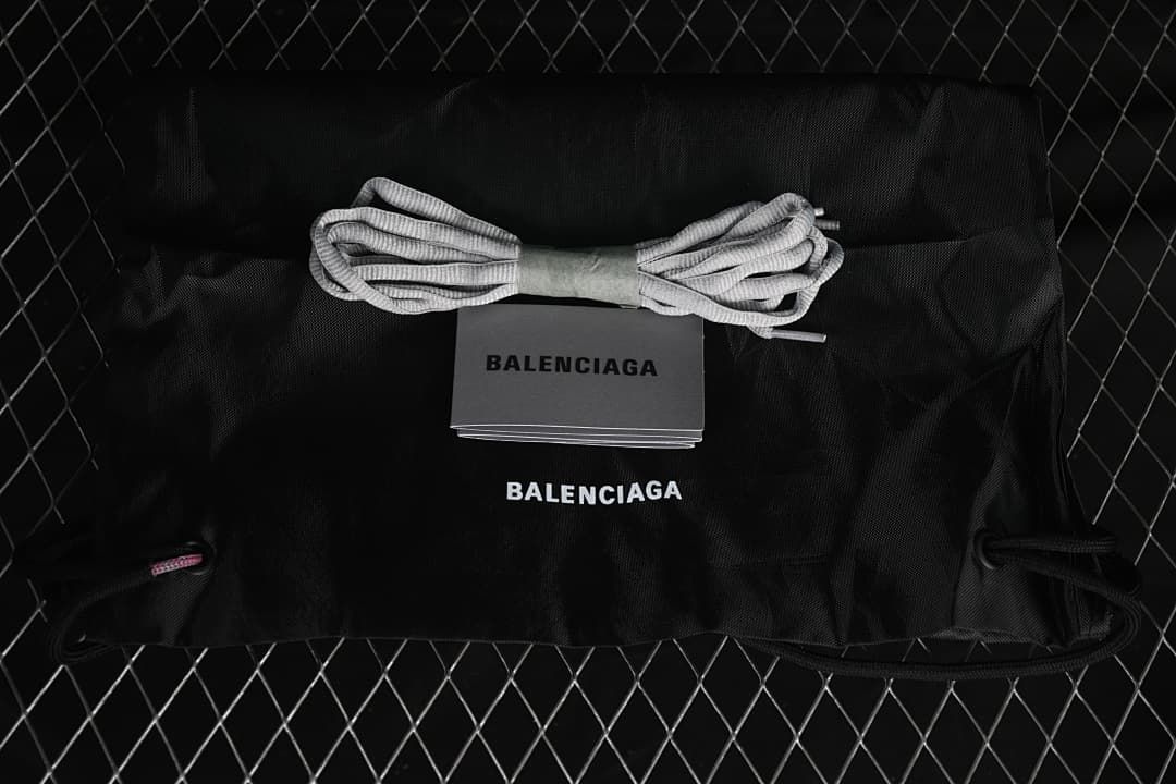 Black drawstring shoe bag and spare gray laces displayed with a Balenciaga-branded card.