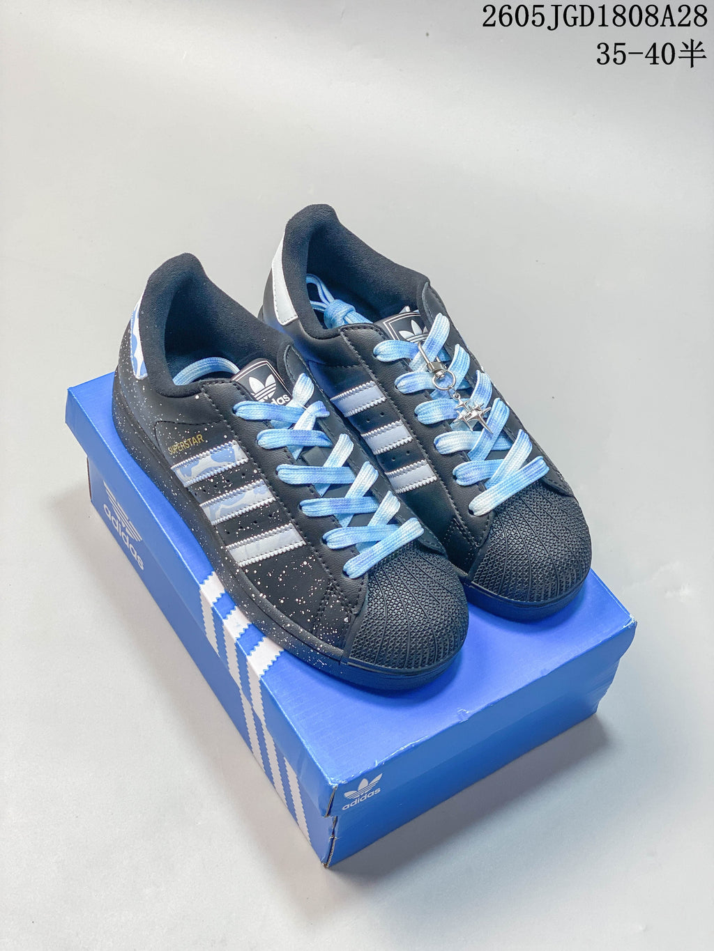 Pair of charcoal Adidas Originals Superstar sneakers with light blue laces and a blue shoebox