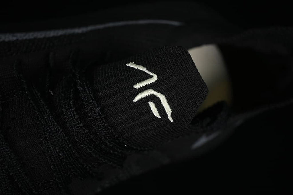 Close-up of embroidered white logo on the black tongue