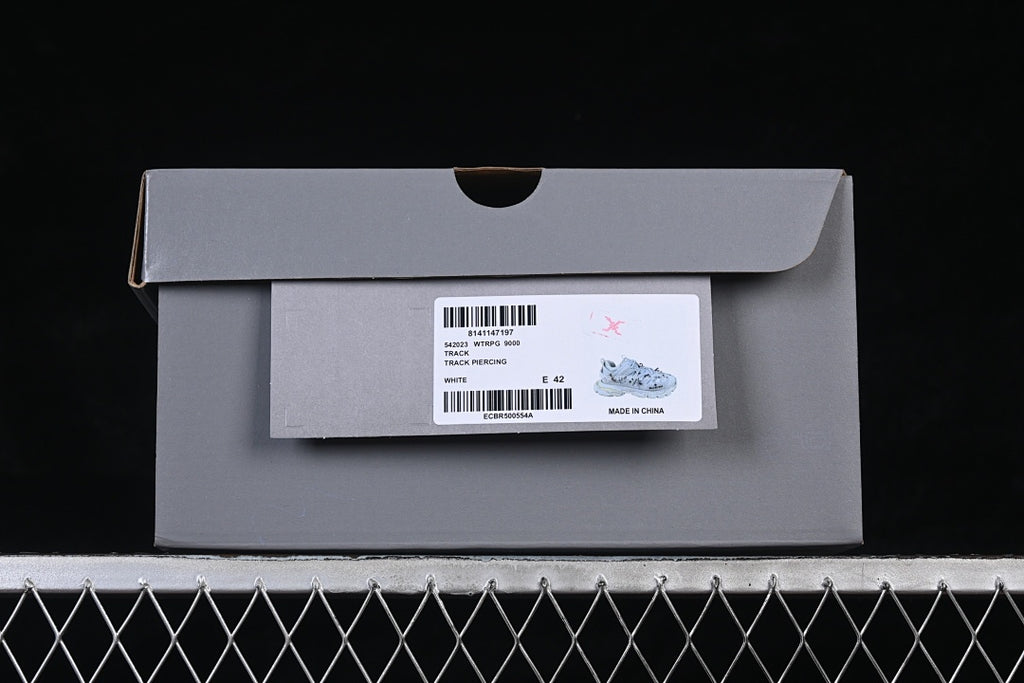 Shoebox label identifies the style as Track Piercing in white and shows EU size 42.