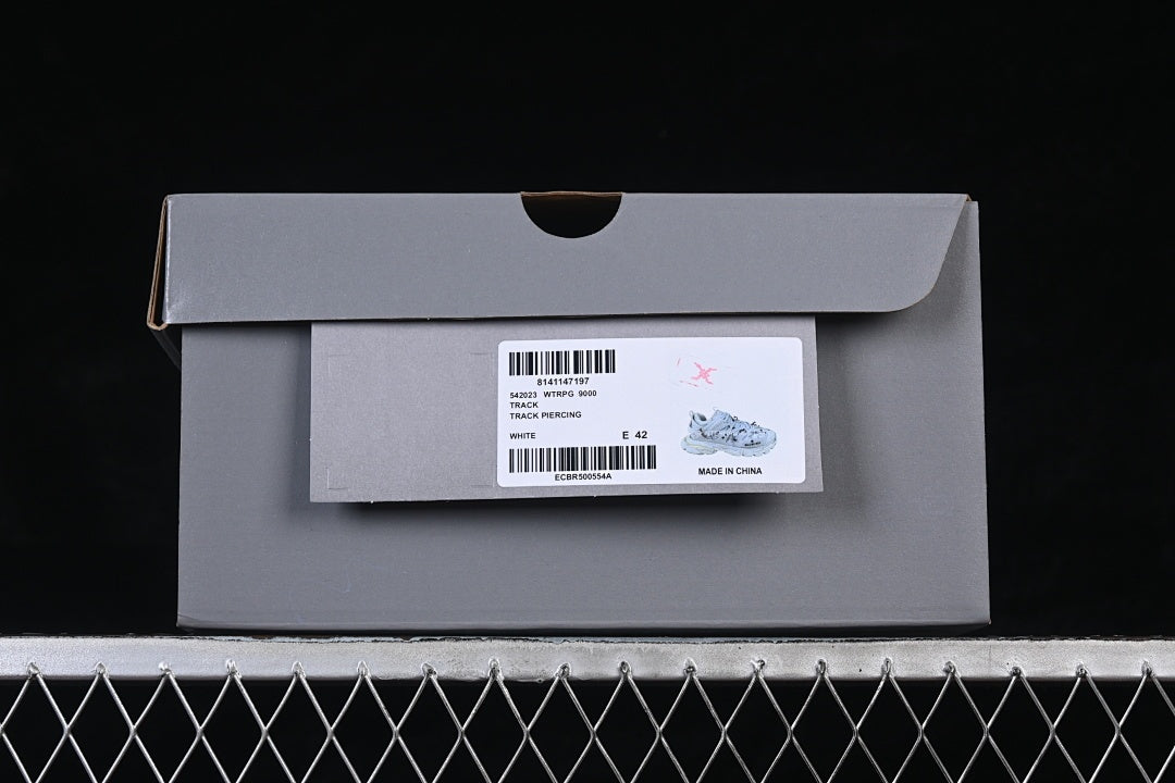 Shoebox label identifies the style as Track Piercing in white and shows EU size 42.