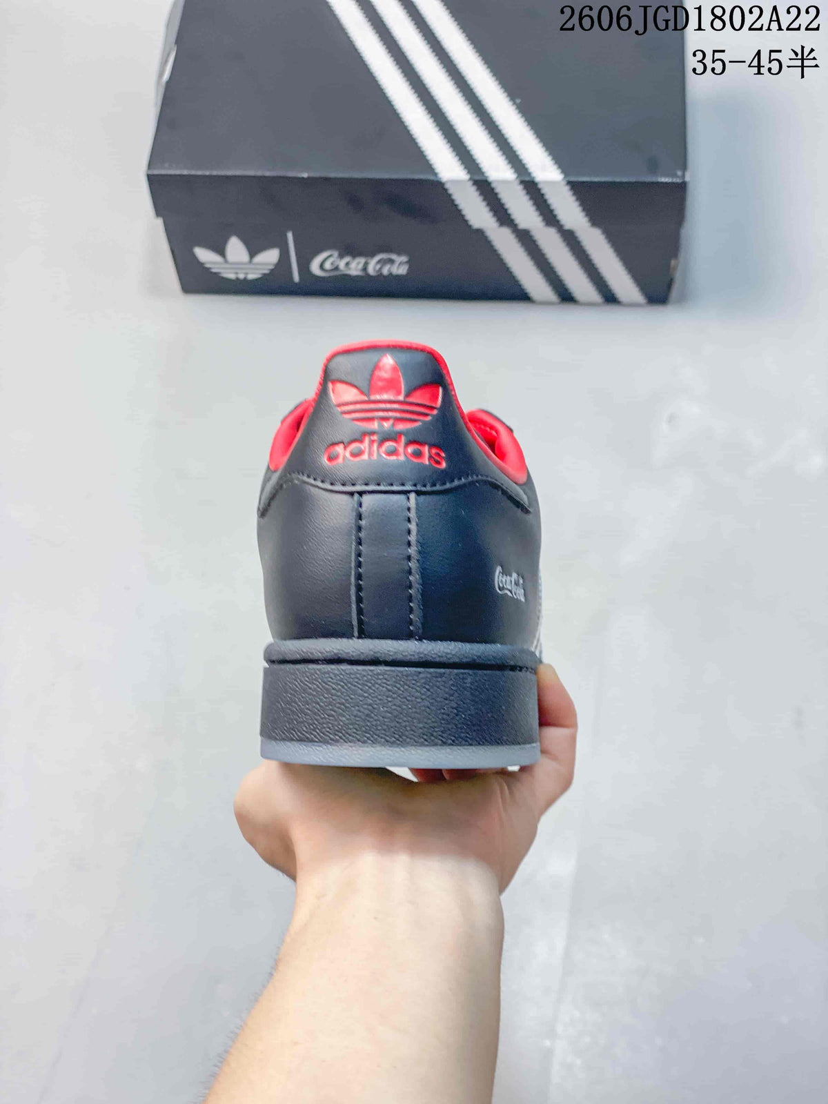 Rear view of the charcoal gray sneaker with red collar lining and Adidas trefoil heel branding.