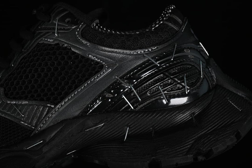 Close-up of the layered side panels, mesh, reflective-looking details, and sole.