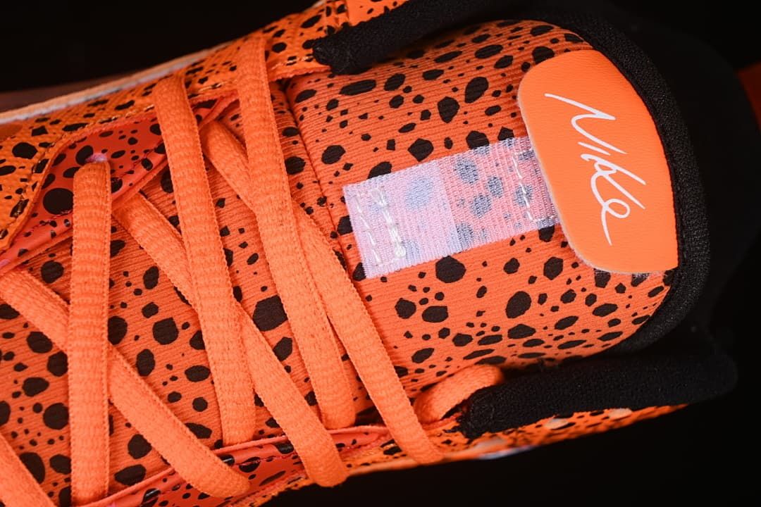 Top close-up of orange laces, patterned tongue, and tongue branding.