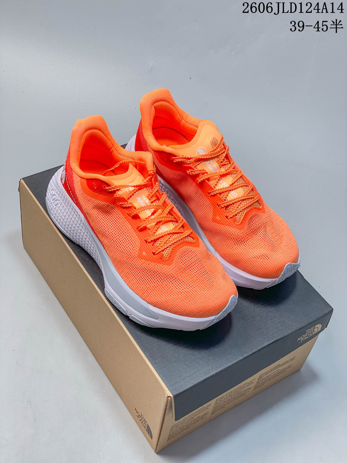 Pair of bright orange The North Face trail-running shoes on a shoebox