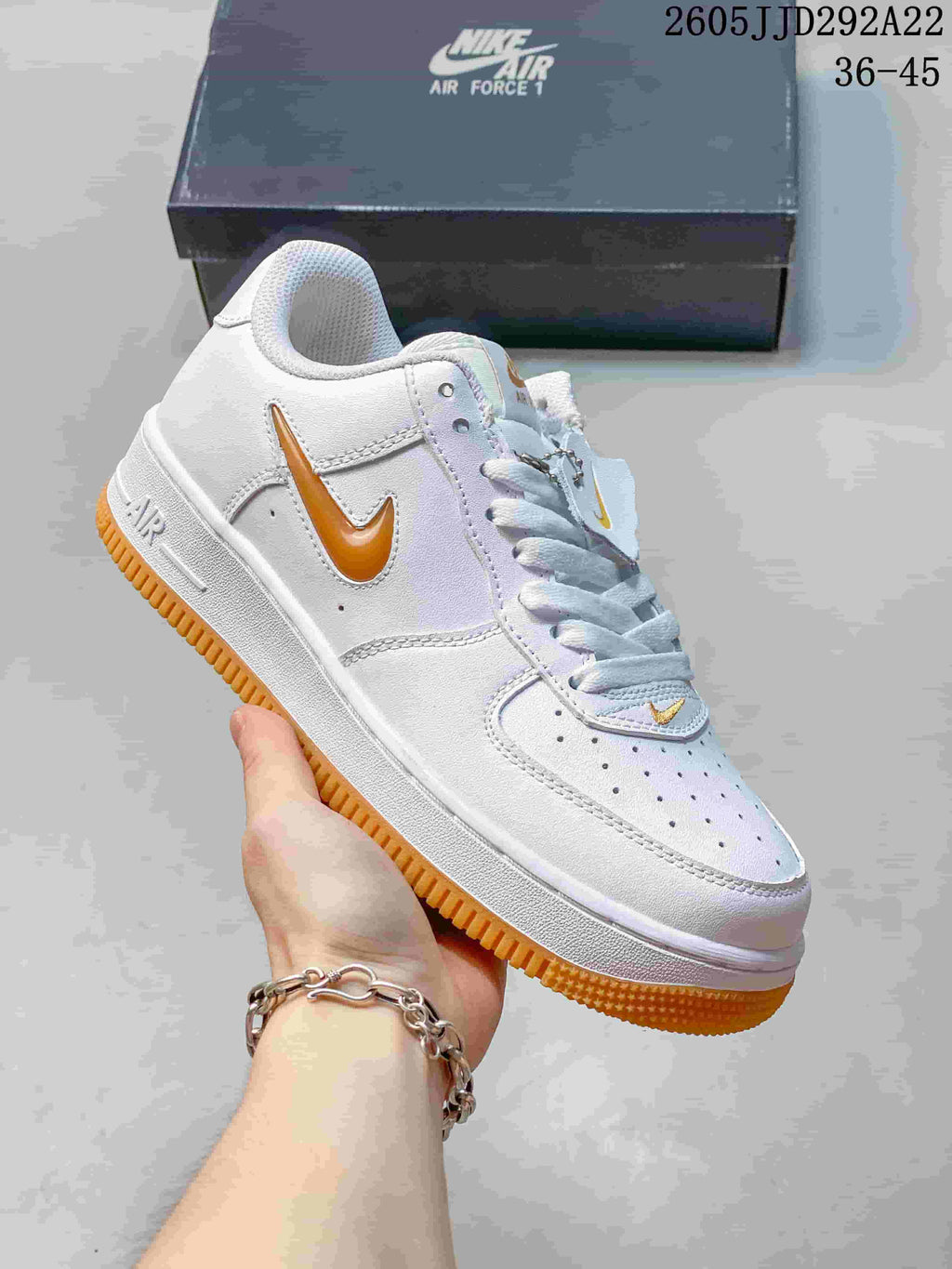 White low-top sneaker with orange Swoosh details and a gum-colored outsole.