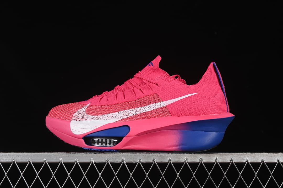 Side view of a pink Nike Zoom Alphafly Next% 3 running shoe with blue accents and a white Swoosh.