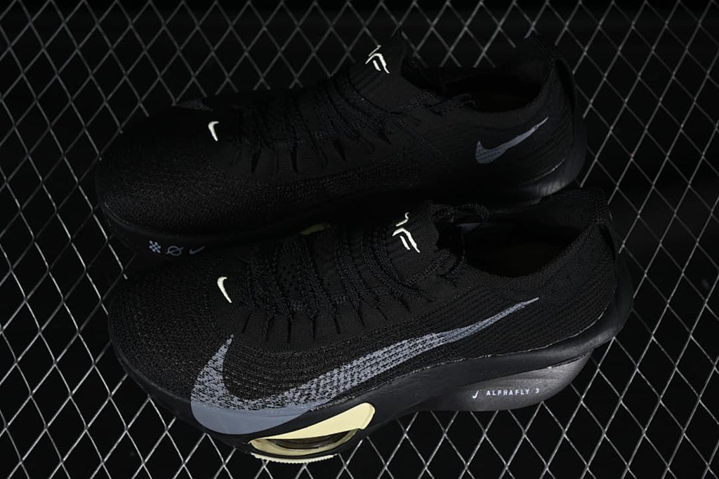 Pair of black running shoes with silver Swoosh details on a display surface
