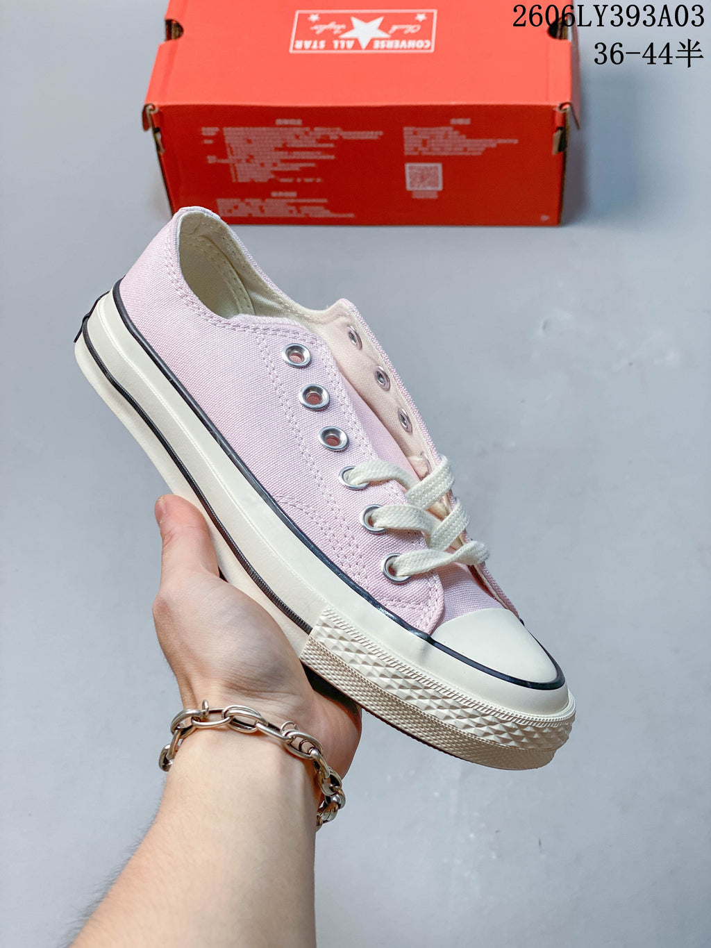 Pale pink low-top Converse-style lace-up sneaker with an off-white sole and black stripe