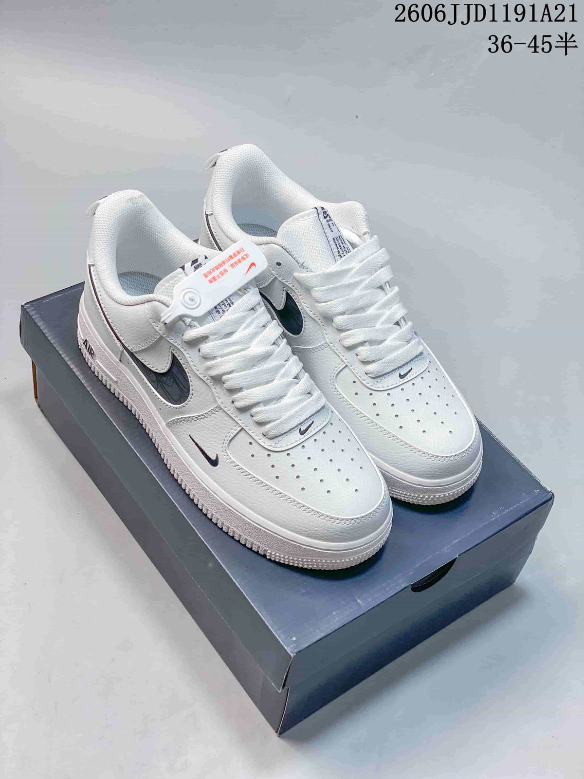 Pair of white low-top sneakers with dark patterned side panels and small contrast Swoosh details.