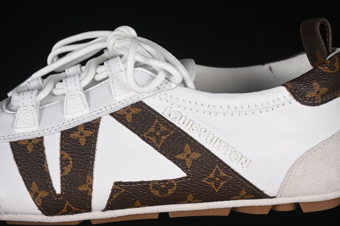Side detail of the white lace-up sneaker with brown patterned accents and raised lettering.