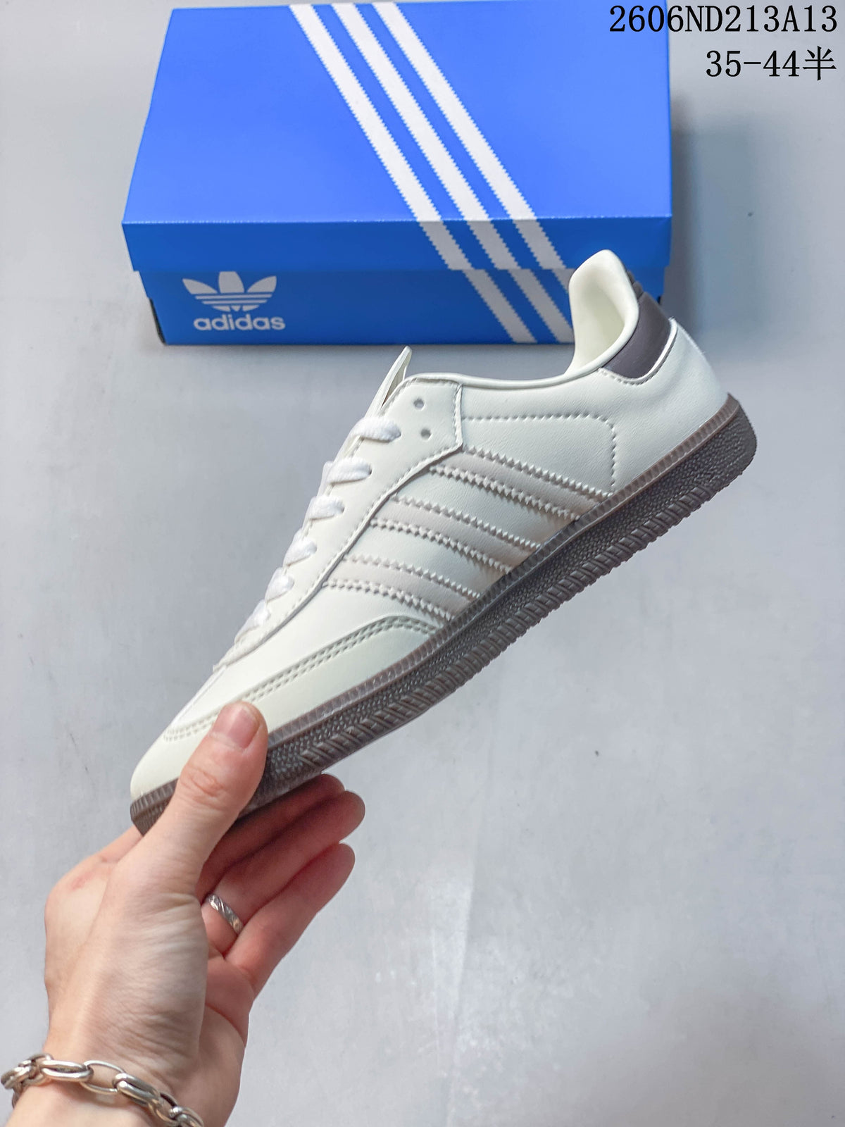Side profile of a white adidas Samba OG sneaker with grey stripes and outsole