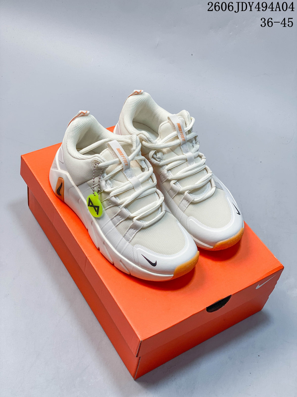Pair of light-colored Nike Free Metcon 7 training shoes with orange outsole accents on an orange shoe box.