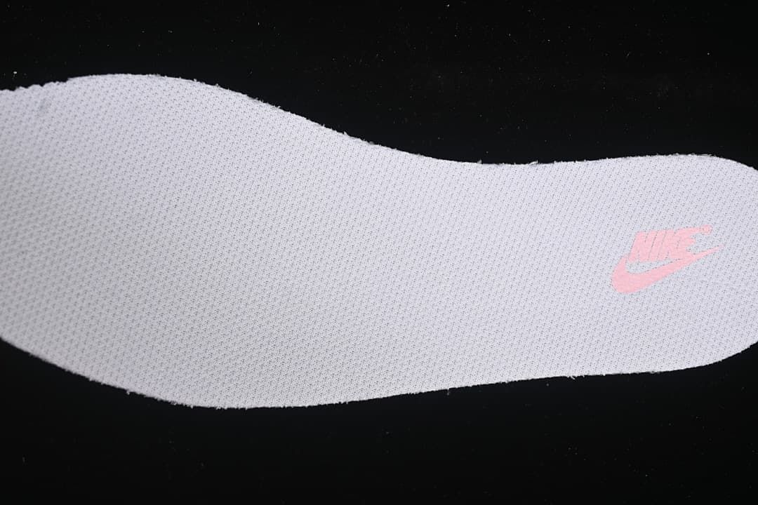 Close-up of a light-colored shoe insert with a pink Nike logo