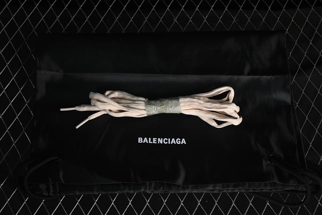 Extra beige laces displayed on a black branded drawstring bag