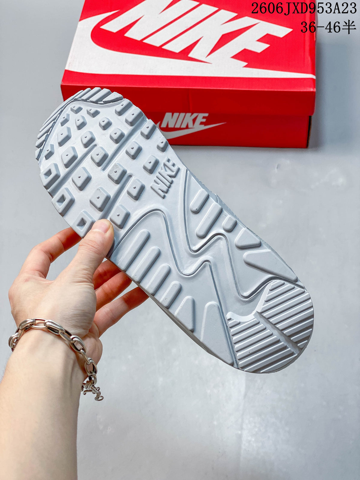 Close-up of the patterned outsole on a light grey Nike Air Max 90 sneaker