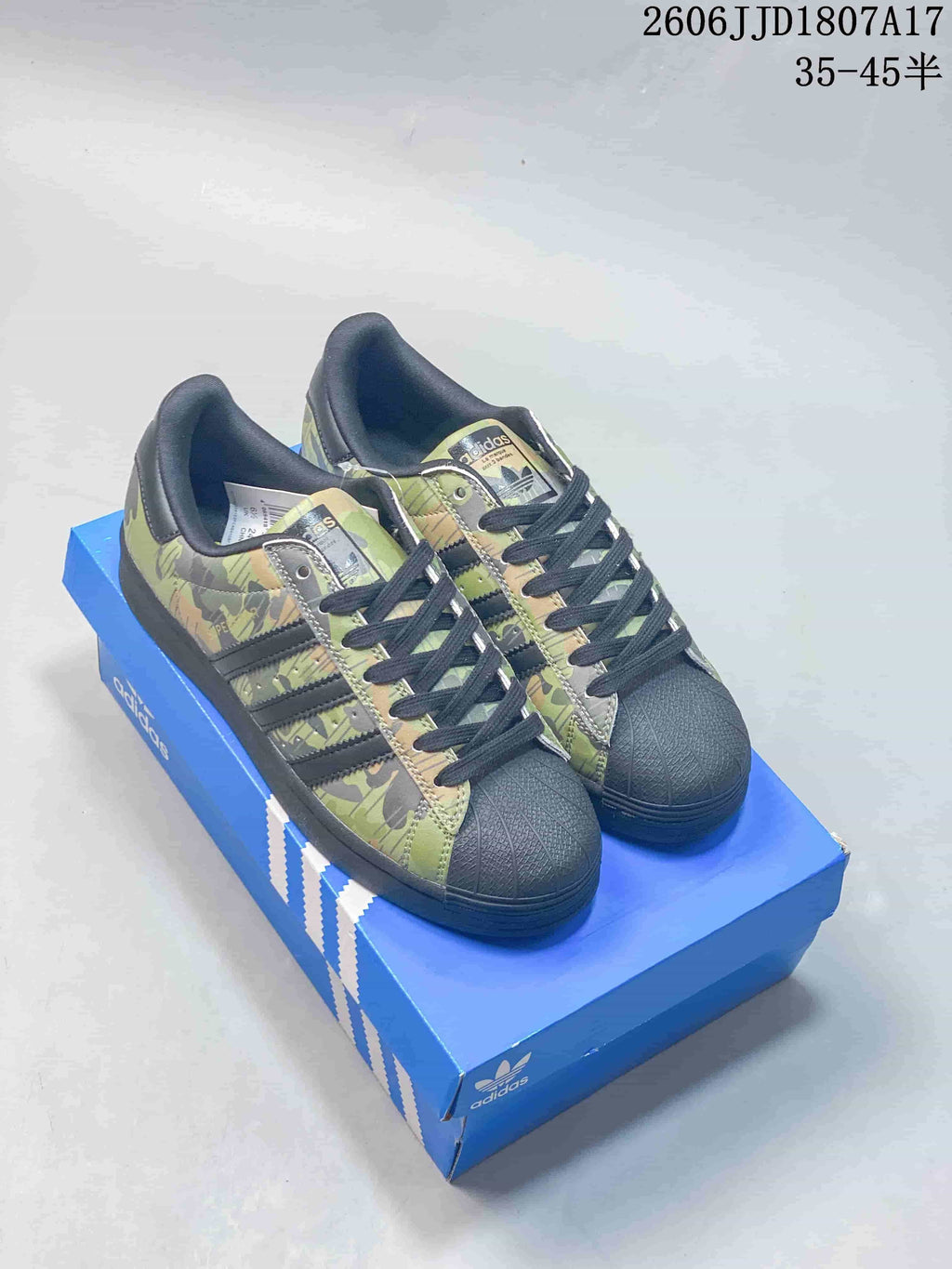 Pair of camouflage adidas Originals Superstar low-top sneakers with black shell-style toes and laces